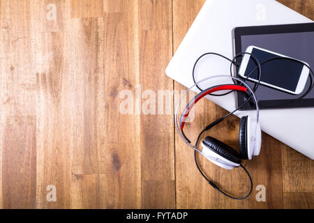 Dispositivi digitali e cuffie su una scrivania in legno Foto Stock