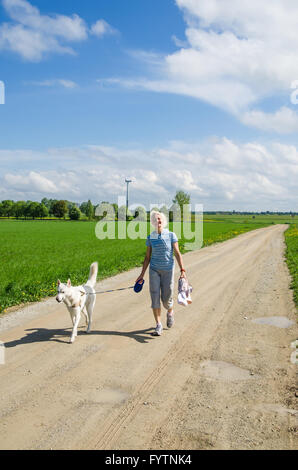 Donna con un cane va sulla strada di un paese Foto Stock