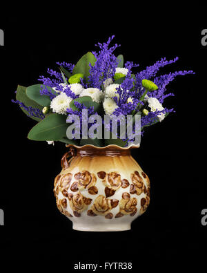 Bel bouquet di colore bianco e verde crisantemi, solidago fiori e foglie di eucalipto in vaso su sfondo nero. Foto Stock