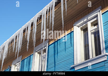 Pericoloso ghiaccioli sospesi dal tetto di una casa in legno Foto Stock