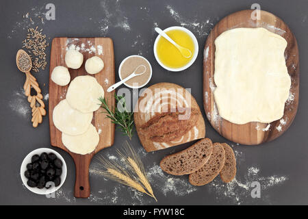 Pane rustico focaccia con cottura ingredienti di impasto su schede di acero, olio di oliva, lievito, erbe, guaine di frumento e di segala grano. Foto Stock