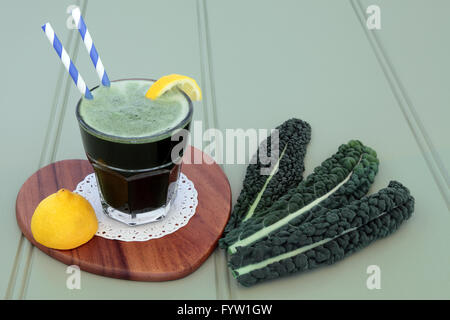 Kale health drink con verdure fresche foglie di limone e frutta di legno su sfondo verde. Ricco di vitamine e antiossidanti. Foto Stock