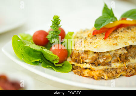 Closeup elegante che serve di lasagne e insalata di piccola seduta sulla piastra bianca Foto Stock