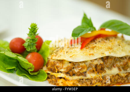 Closeup elegante che serve di lasagne e insalata di piccola seduta sulla piastra bianca Foto Stock