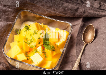Budino dessert servito con mango e il trito di foglie di menta Foto Stock