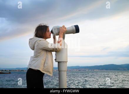 Donna cerca in pay binocolo Foto Stock