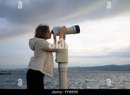 Donna cerca in pay binocolo Foto Stock