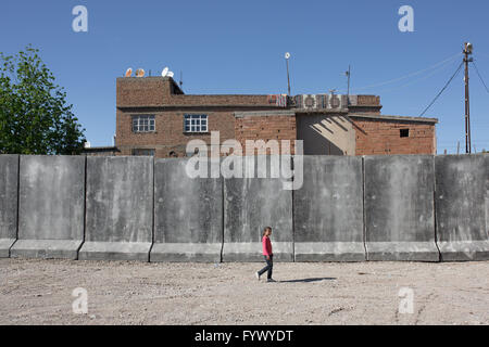 Un bambino è visto camminando accanto alle mura erette da parte delle forze di sicurezza per bloccare alcune parti del Sur, Diyarbakir, Turchia il 18/4/16. Il round-the-clock coprifuoco a Sur distretto di Diyarbakir, la Turchia si è conclusa dopo 103 giorni. Il quartiere degli abitanti di lotta per tornare a una vita normale, mentre per 5 quartieri che erano totalmente rovinata durante gli scontri tra l esercito e il curdo gruppo armato YPS, ingresso è forbidded per i civili. Foto Stock