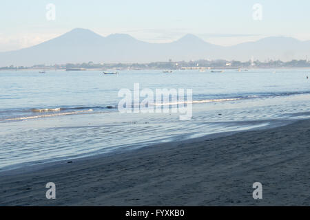 La baia di Jimbaran, Bali, nelle prime ore del mattino con le barche dei pescatori e le montagne in distanza. Foto Stock