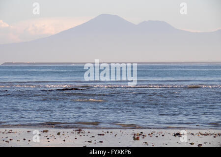 La baia di Jimbaran, Bali, nelle prime ore del mattino con le montagne e l'aeroporto di Bali in pista la distanza. Foto Stock