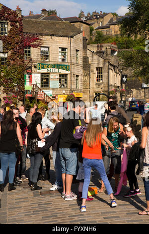 Regno Unito, Inghilterra, Yorkshire, Calderdale, Hebden Bridge, Bridge, porta i visitatori in St Georges Square godendo del sole Foto Stock