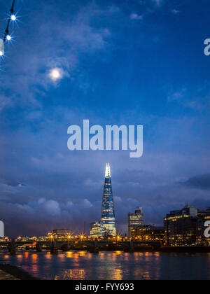 La Shard brilla come la luna sorge in un nuvoloso blu cielo al crepuscolo Foto Stock