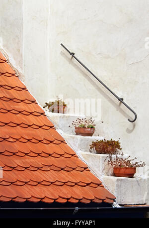 Frammento di un tetto rosso piastrella sul muro bianco sullo sfondo Foto Stock