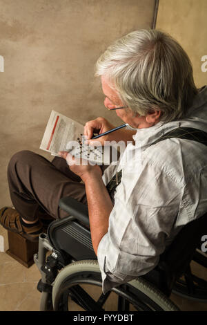 Titolare di pensione o di rendita in una casa di cura risolvere cruciverba Foto Stock