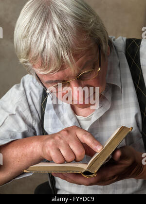Uomo anziano con gli occhiali per leggere un libro Foto Stock