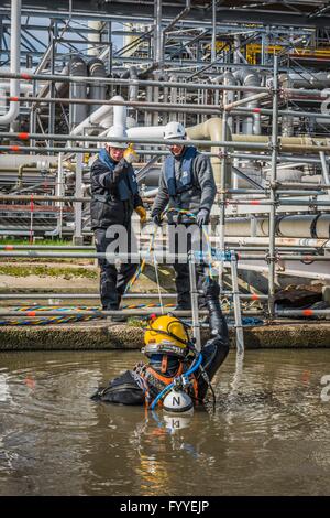 I subacquei industriali sono altamente specializzati lavoratori, spesso svolgono i loro compiti sotto complicati e difficili condizioni.Un subacqueo industriale in una moderna drysuit riparato in un impianto chimico a Stade tubi di collegamento sottomarino. Foto: 2016, 06 aprile. Foto Stock