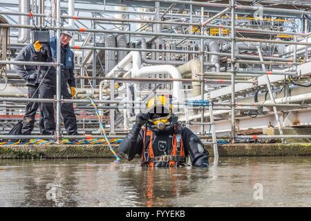 I subacquei industriali sono altamente specializzati lavoratori, spesso svolgono i loro compiti sotto complicati e difficili condizioni. Un subacqueo industriale in una moderna drysuit riparato in un impianto chimico a Stade tubi di collegamento sottomarino. Foto: 2016, 06 aprile. Foto Stock