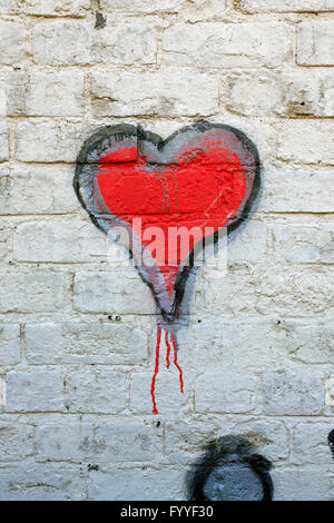 Cuore rosso graffiti su un dipinto di bianco muro di mattoni Foto Stock