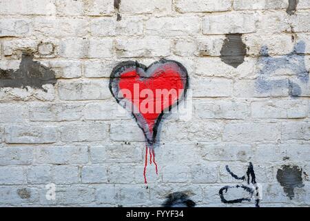 Cuore rosso graffiti su un dipinto di bianco muro di mattoni Foto Stock