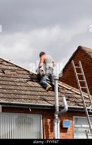 Workman la riparazione del crinale delle tegole di un tetto Foto Stock