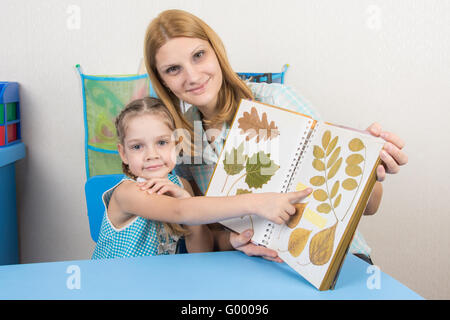 Cinque anni di ragazza e madre esaminando Herbarium mostra su uno dei fogli dell'album, e guardò nel telaio Foto Stock