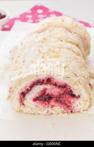 Involtino di meringa. Rotolo di meringa con crema di latte fresco e di frutti a bacca rossa. Macro, il fuoco selettivo Foto Stock