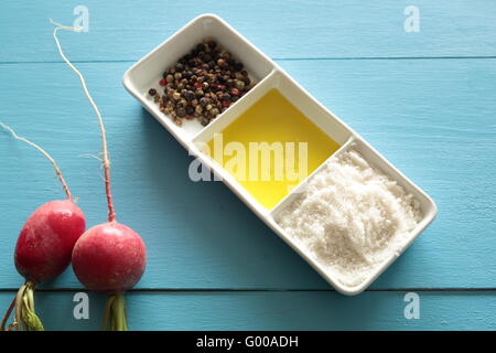 Ravanelli su due blu sullo sfondo di legno con sale e olio e pepe Foto Stock