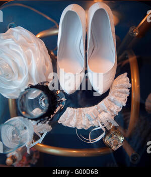 Bianco scarpe nuziale e altri attributi di nozze su un tavolo Foto Stock