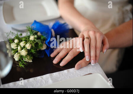 Closeup ritratto di groom holding spose in mano sul tavolo vicino a bouquet Foto Stock