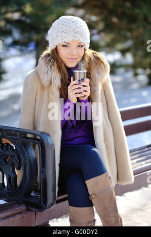 Bella sorridenti inverno donna con la tazza esterna. Ridendo Foto Stock