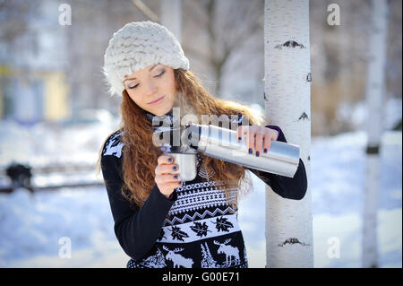 Bellissima ragazza con il thermos e la tazza di tè caldo nel gelido inverno giorno Foto Stock