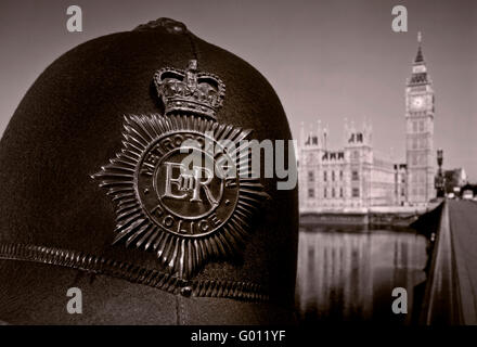 Polizia LONDRA 1960's Metropolitan casco di polizia vicino vista sullo storico casco retrò con le Case del Parlamento e il Tamigi dietro Westminster UK B&W. Foto Stock