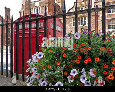 Estate nelle petunie con telefono rosso scatola e Abbot's Hospital un giacobino alms house dietro Guildford Surrey UK Foto Stock