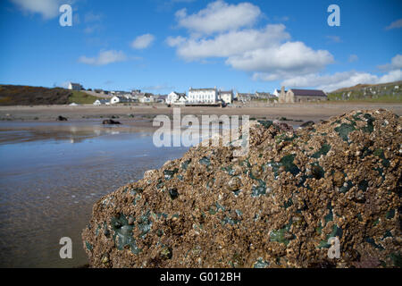 La vista verso Aberdaron village (mostra pub & chiesa) presi dalla spiaggia con la bassa marea su un estate giornata di primavera con il blu del cielo Foto Stock