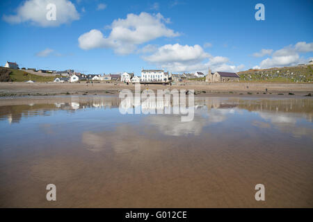 La vista verso Aberdaron village (mostra pub & chiesa) presi dalla spiaggia con la bassa marea su un estate giornata di primavera con il blu del cielo Foto Stock