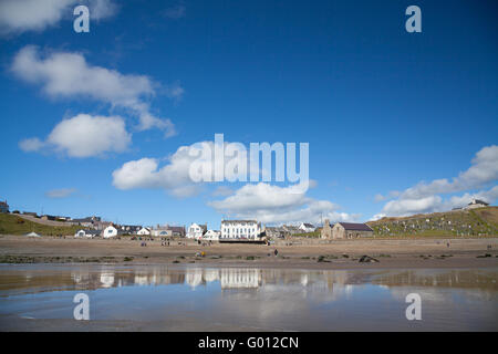 La vista verso Aberdaron village (mostra pub & chiesa) presi dalla spiaggia con la bassa marea su un estate giornata di primavera con il blu del cielo Foto Stock