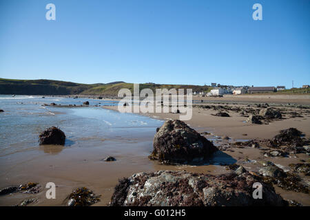 La vista verso Aberdaron village (mostra pub & chiesa) presi dalla spiaggia con la bassa marea su un estate giornata di primavera con il blu del cielo Foto Stock