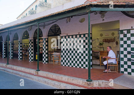 Minorca isole Baleari, Spagna, Europa: un macellaio seduto sotto i portici del mercato di piazza Plaza de la Libertad in Ciutadella Foto Stock