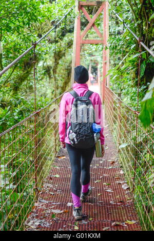 Alpinista femmina attraversando un ponte di sospensione Foto Stock