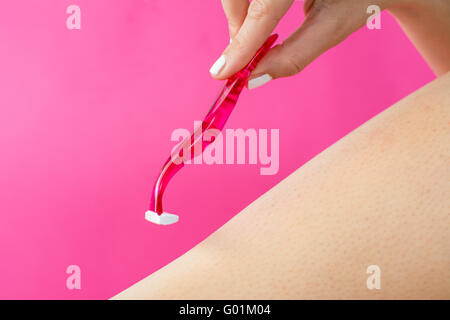La donna la rasatura la sua gamba con rasoio rosso Foto Stock