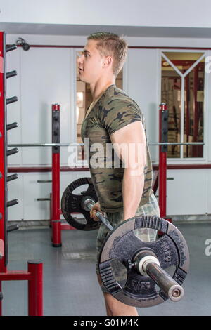 L'uomo eseguendo barbell curl in palestra. Allenamento bicipiti Foto Stock