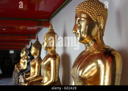 La fila di golden statue di Buddha nel tempio thailandese Foto Stock