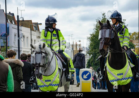 Montate i funzionari di polizia guardare oltre i tifosi di calcio che sono sulla loro strada per la partita. Foto Stock