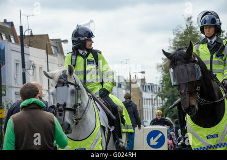 Montate i funzionari di polizia guardare oltre i tifosi di calcio che sono sulla loro strada per la partita. Foto Stock