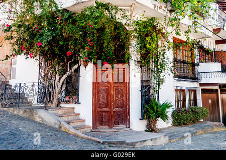 Porte di legno intagliato in Puerto Vallarta la Zona Romantica, con bouganville, letti in ferro battuto con aggiunta di romanticismo per l'edificio bianco Foto Stock