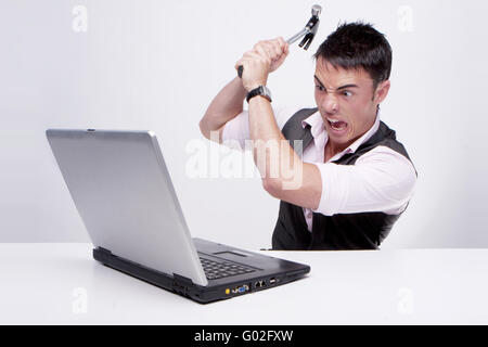 Brunette imprenditore guarda al suo computer per l'incredulità di uccidere il suo computer usando un martello Foto Stock