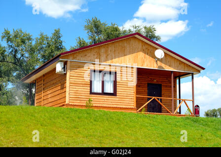 La casa in legno con un prato su uno sfondo di cielo blu Foto Stock