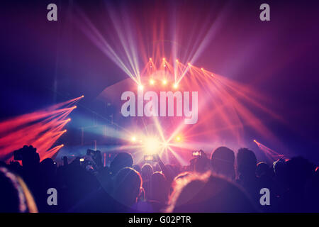 Gruppo di grandi dimensioni di un felice giovani godendo di concerto, avendo divertimento di trascorrere del tempo in un night club, dancing in luminosi raggi laser Foto Stock