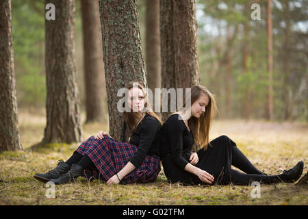 Le ragazze adolescenti pensively seduto a terra nella foresta. Foto Stock