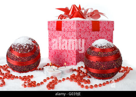 Regalo di natale Scatola nella neve con palline rosse e candele Foto Stock